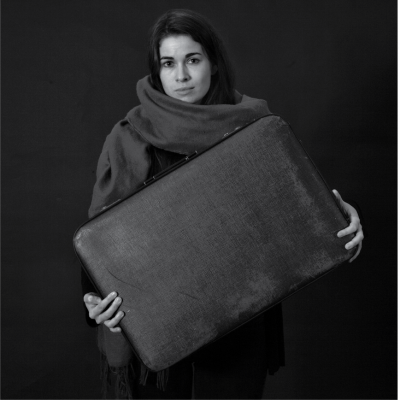 Black and white photo: Woman in shawl with suitcase