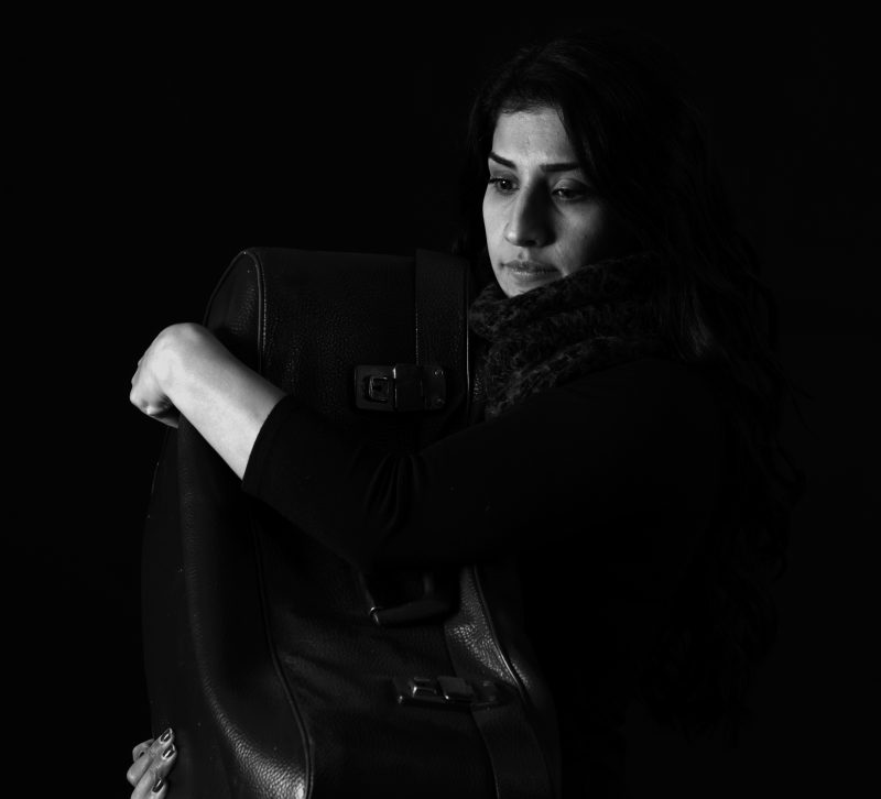Black and white photo: Woman in black with suitcase